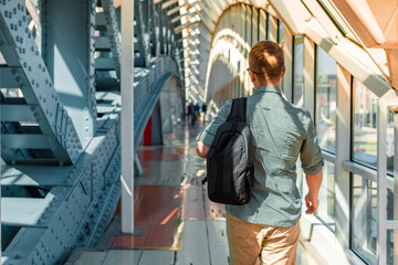Obraz na płótnie Canvas A young man in sunglasses and a shirt walks along a modern glass business corridor