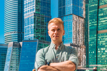 Portrait of a young business man in a shirt at the glass skyscrapers