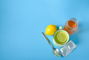 Infusion based on lemon and ginger, with honey, accompanied by other medicines, on a blue...