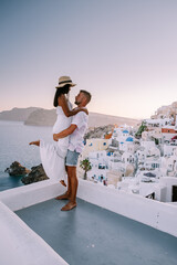 Santorini Greece, young couple on luxury vacation at the Island of Santorini watching sunrise by...