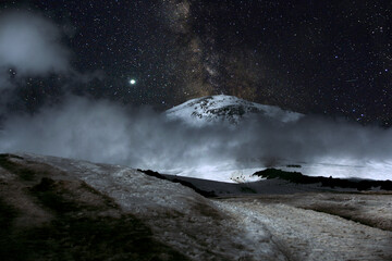 Climbing Elbrus. Snow-capped mountain peaks and figures of climbers at night. The mountains are covered with snow at night.