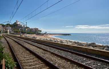 Rail way through a beach to a town with the coast next to it