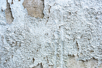 Paint bubbling and blistering on the old concrete wall.
