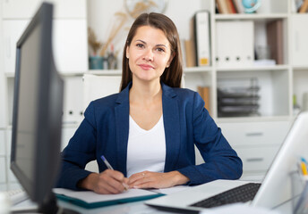 Portrait of smiling successful business woman working on laptop in modern office ..
