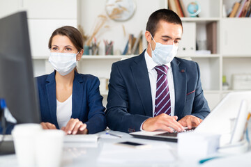 Manager in protective medical mask gives task to assistant at office