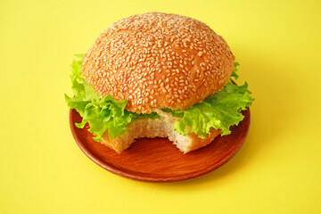bitten fresh vegan burger with lettuce and tomato. healthy and vegetarian food.