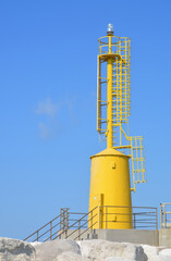 yellow lighthouse with metal structure on concrete base