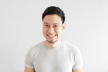 Smile face of happy Asian man wear grey t-shirt and on grey background.