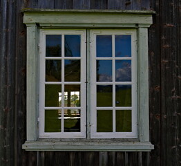Classical old window with white window frame and brown varnished wooden walls.