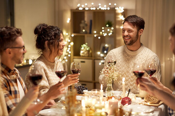 holidays, celebration and people concept - happy friends having christmas dinner party drinking non-alcoholic red wine at home