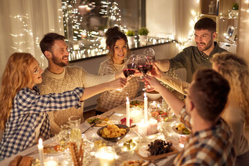holidays, celebration and people concept - happy friends having christmas dinner at home drinking non-alcoholic red wine