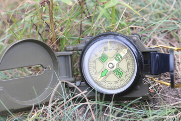 round compass on background of summer grass as symbol of tourism with compass, travel with compass...