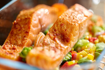 food, eating and culinary concept - close up of salmon fish with vegetables in baking dish on kitchen table at home