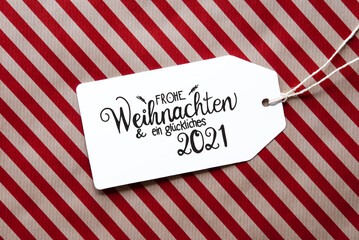 Label With German Calligraphy Frohe Weihnachten Und Ein Glueckliches 2021 Means Merry Christmas And A Happy 2021. Red Wrapping Paper As Background