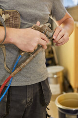 Lackierer reinigt die Düse seiner Sprühpistole