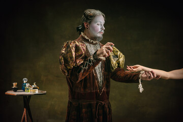 Disinfecting hands. Young man as Johann Bach isolated on dark green background. Retro style, comparison of eras concept. Beautiful male model like historical character, great music composer, old