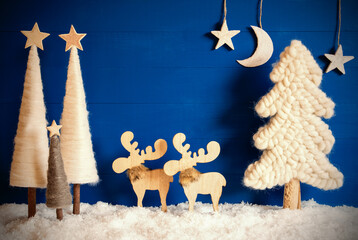 Copy Space On Blue Wooden Background With Snow. Decoration And Ornament Like Christmas Trees, Stars, Moon And A Moose Couple.