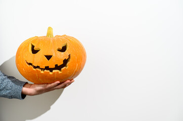 Crop Male hand holds a carved Halloween pumpkin on white background. Halloween symbol. Copy space