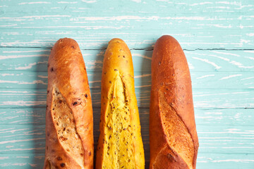 Three crispy french baguettes lie on an old wooden table with free space for text