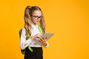 Schoolgirl Using Tablet Computer Doing School Homework Standing In Studio