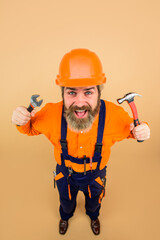 Repairment tools. Worker in hard hat holds hammer. Building. Industry. Technology. Bearded builder. Builder in construction helmet. Hard hat. Industrial worker.