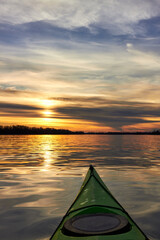 Bow of green kayak at colorful sunset over Danube river at autumn time