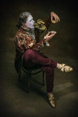 Eating an oyster. Young man as Johann Bach isolated on dark green background. Retro style, comparison of eras concept. Beautiful male model like historical character, great music composer, old