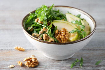 Fruit salad with pears, arugula, walnuts and Roquefort cheese. Delicacy appetizer in bowl on gray background