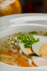 Fresh soup with vegetables, meat and eggs in a white plate.