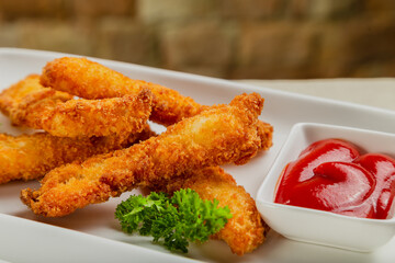 Fresh crispy nuggets with tomato sauce on a white plate.