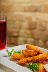 Fresh crispy nuggets with tomato sauce on a white plate.