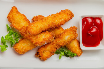 Fresh crispy nuggets with tomato sauce on a white plate.