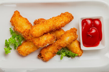 Fresh crispy nuggets with tomato sauce on a white plate.