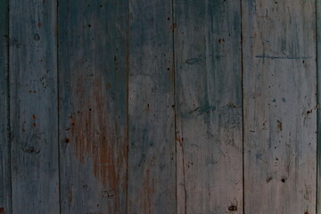 Old worn down plank wall with blue or turquoise paint that has pealed of.