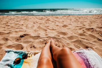 Legs of a girl lying on the beach with the sea in the background