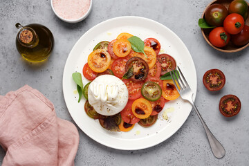 Tomato salad with burrata cheese. Traditional Italian food. Bright multicolored vegetables on plate with spices