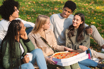 Group of teenagers with take away pizza sitting on ground