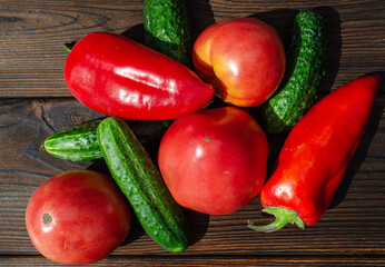 Tomatoes, cucumbers, bell peppers on a wooden background close-up.