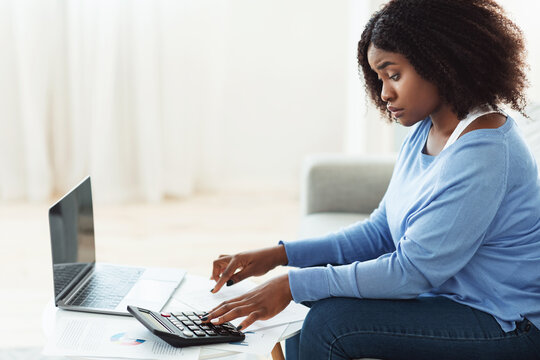 Black Woman Using Calculator And Pc At Home