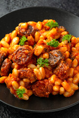 Bean and chorizo stew served in black plate with parsley