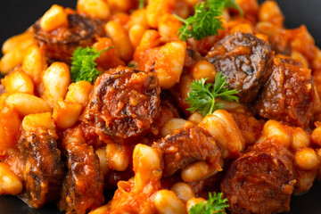 Bean and chorizo stew served in black plate with parsley