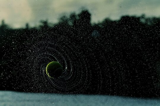 A wet tennis ball spinning in air and creating a unique spiral pattern of water droplets . - Powered by Adobe