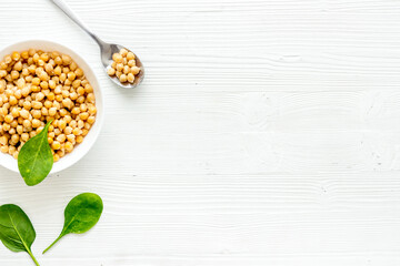 Raw chickpeas in bowl on white kitchen table from above copy space
