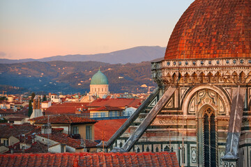 Fototapeta na wymiar Cathedral of Saint Mary of the Flower in Florence. Tourist hotspot in Tuscany. Aerial view of a gothic dome and medieval city in background, illuminated by setting sun. UNESCO World Heritage Site.