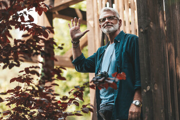 Retired neighbor with a beard greets and smiles on the terrace of the house. Support and care for old people. Thanks to the volunteers for their help.