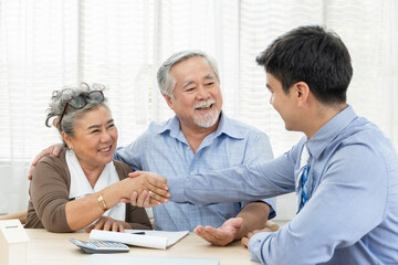 Happy smiling Asian old couple making purchase and mature woman handshake with real estate agent,...