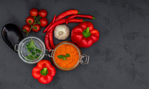 Traditional autumn Balkan spread Ajvar, malidzano or pinjur made of red bell pepper, chili, eggplant, tomatoes, and garlic. Homemade relish. Top view, copy space.