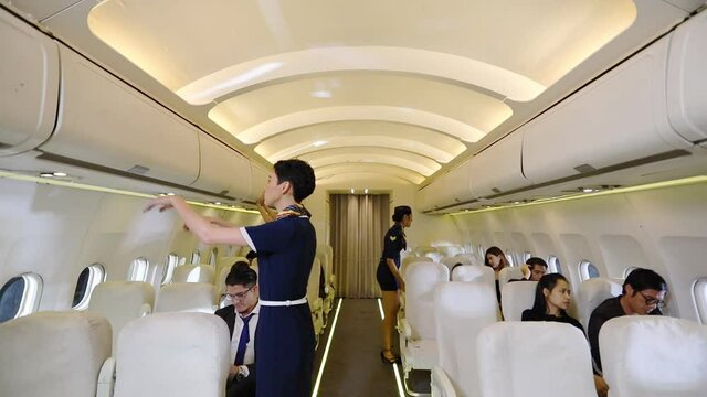 Caucasian flight attendant closing the overhead luggage compartment for final cross check and prepare to take off with slow motion effect
