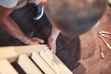 Carpenter hobbyist assembling wooden boards at home / garage.