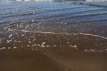 pristine beach in Tasmania with deep blue ocean and dark golden sand